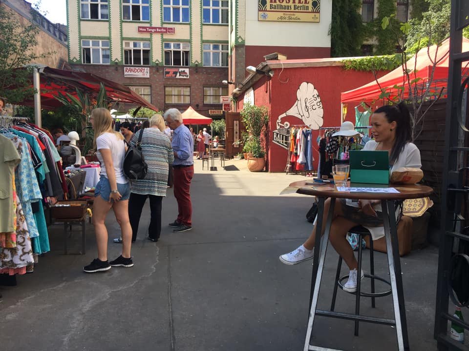 Besucher stöbern an Kleiderständern beim Vintage-Flohmarkt im Hof des Ballhaus Berlin